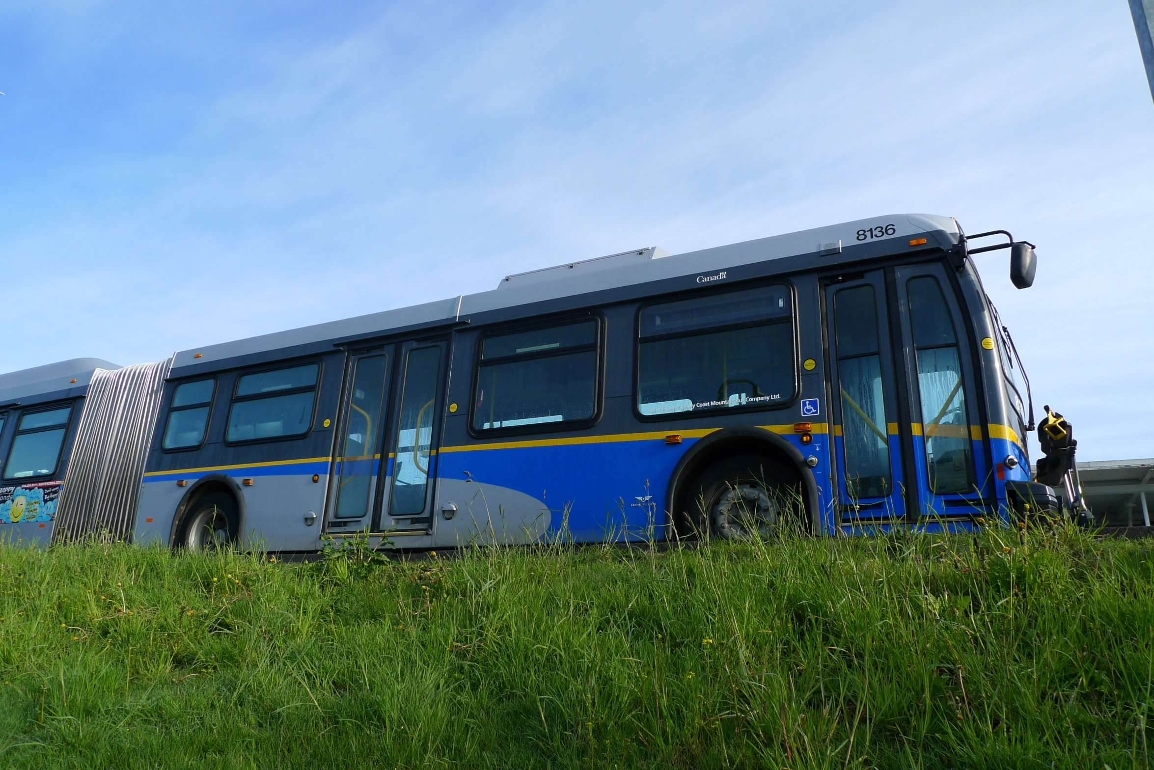 a bus with a ladder sitting on the side of a grass covered field