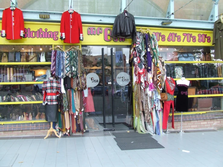 a store front with multiple pieces of clothing outside of it