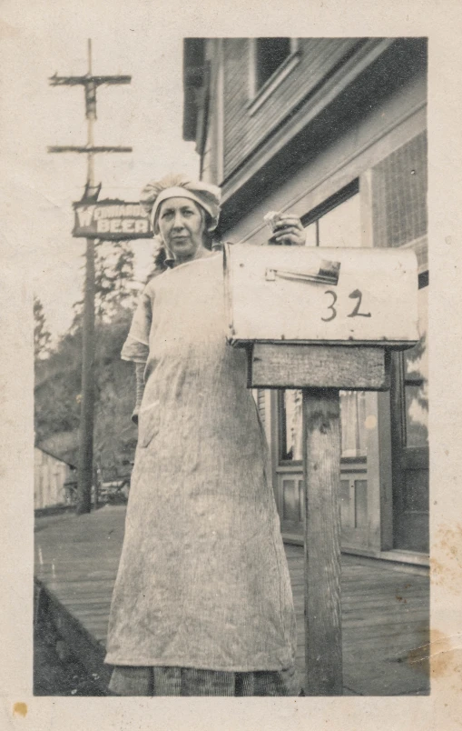 woman in an apron standing in front of a mailbox