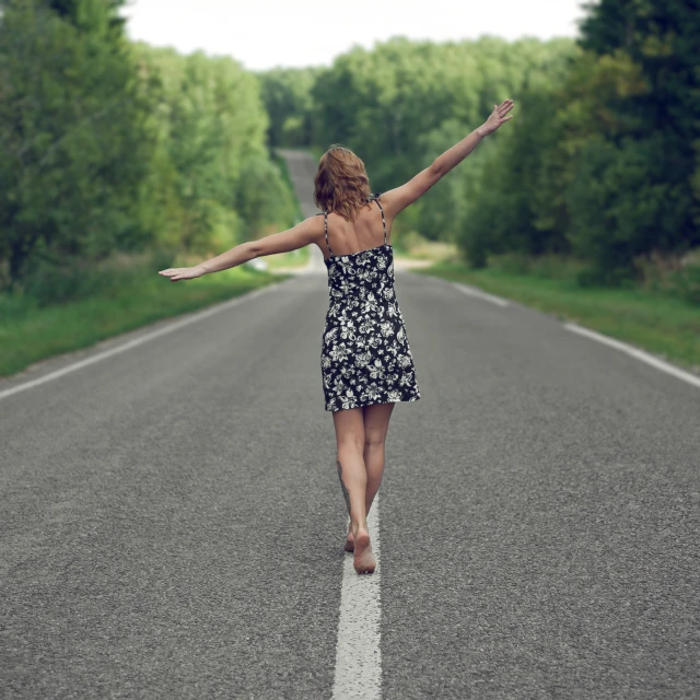 a woman walks along a straight road and stretches her arms