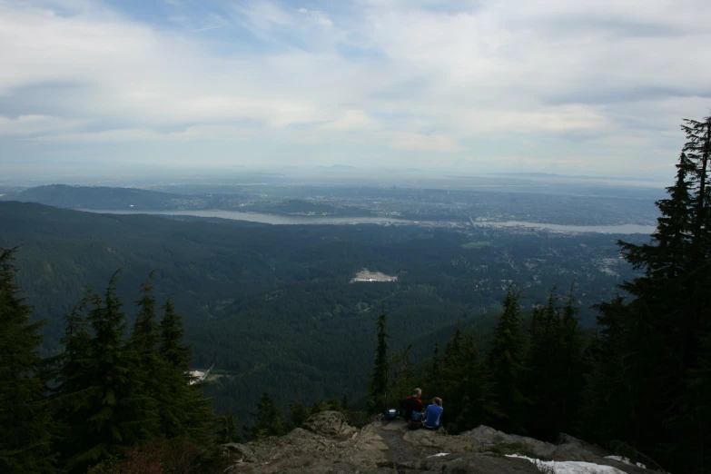 some people sitting on the top of a rock cliff