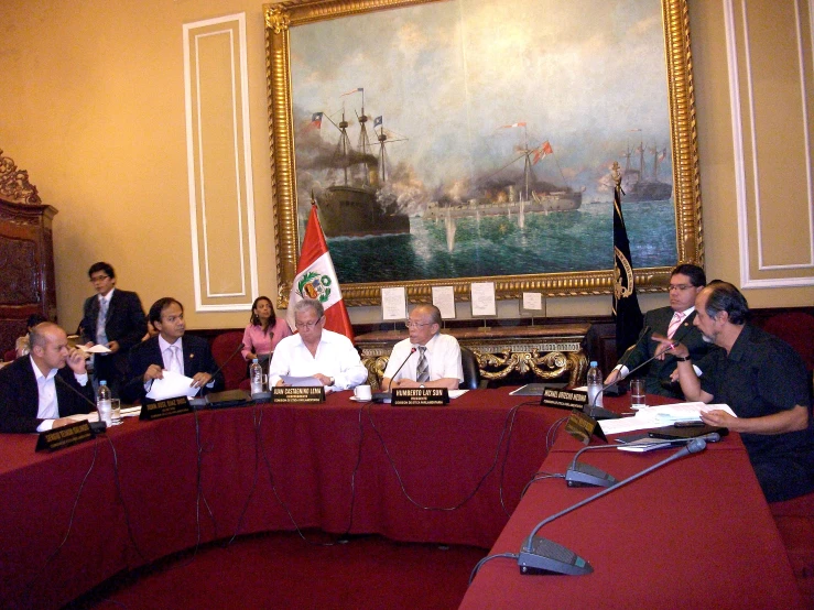 a meeting with men and women sitting at a long table