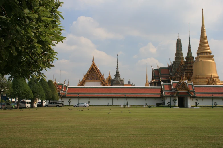 view of the royal palace in thailand with some vehicles parked