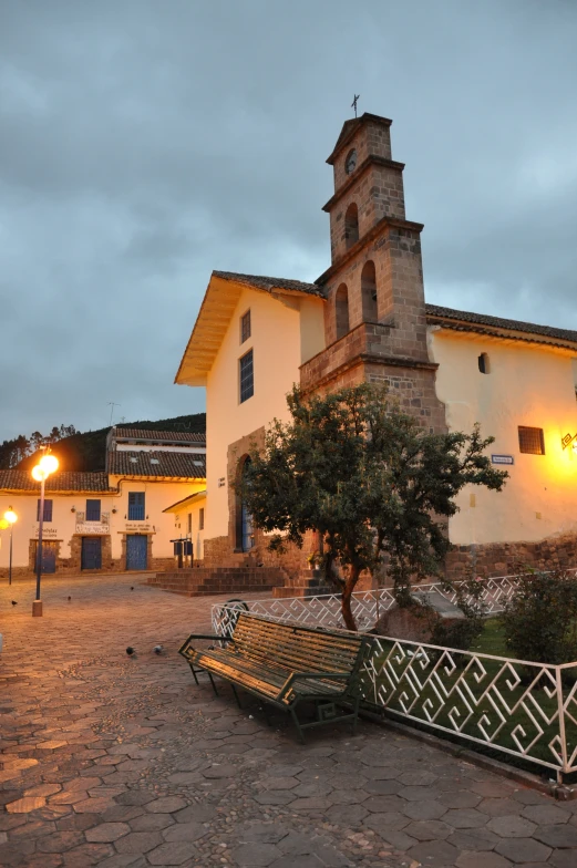 there is a stone and iron bench outside the church