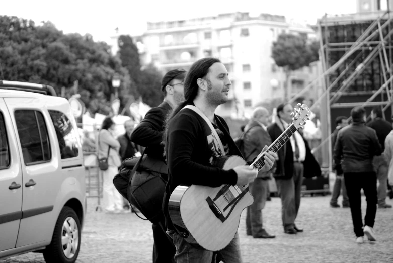 two men playing instruments near parked cars on the street