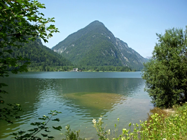 the mountains on the other side of the lake are rising high above the trees