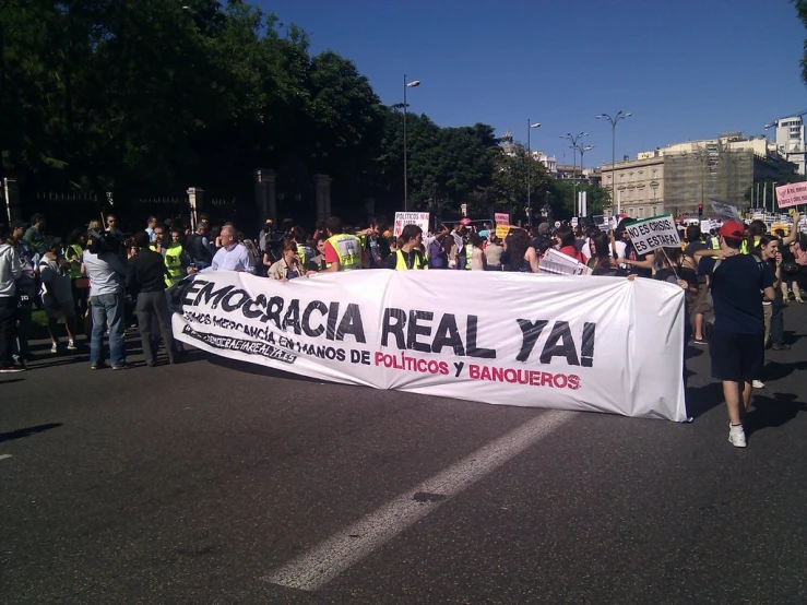 large group of people on the street with a banner