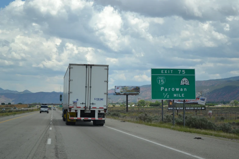 a truck is traveling down a rural road by a sign