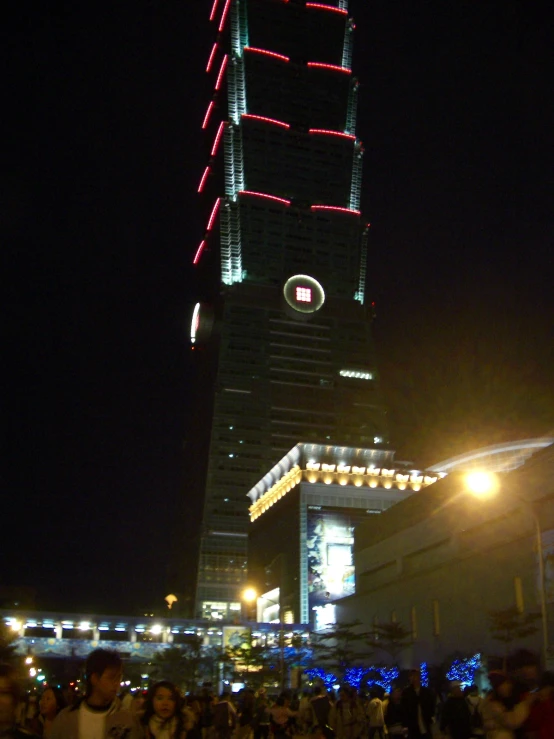 people in the foreground and a building illuminated in red, green and white lights on the other side