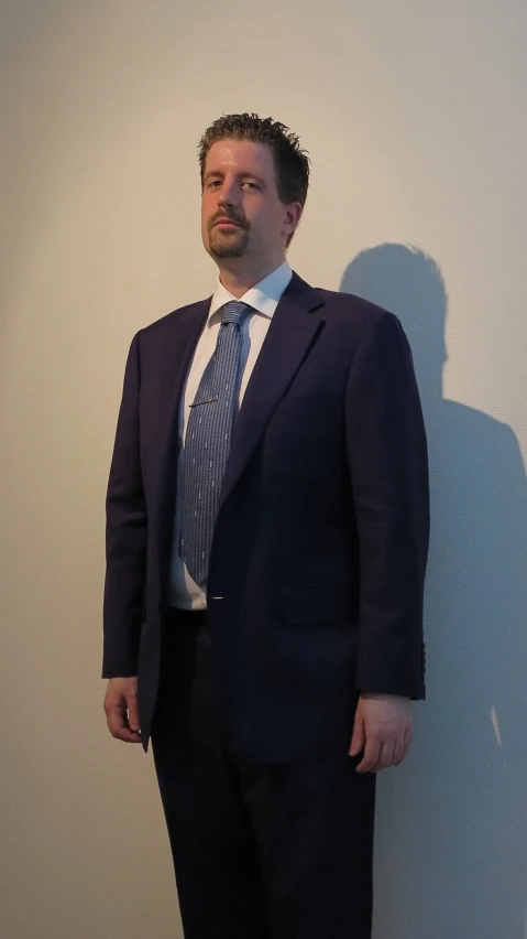 a person in a suit standing up against a wall