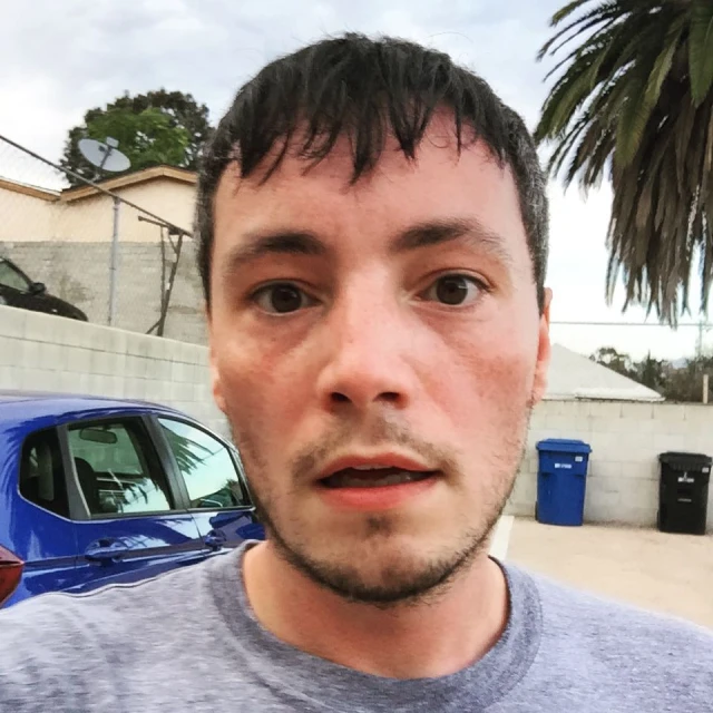 a man poses for a selfie while wearing a blue t - shirt