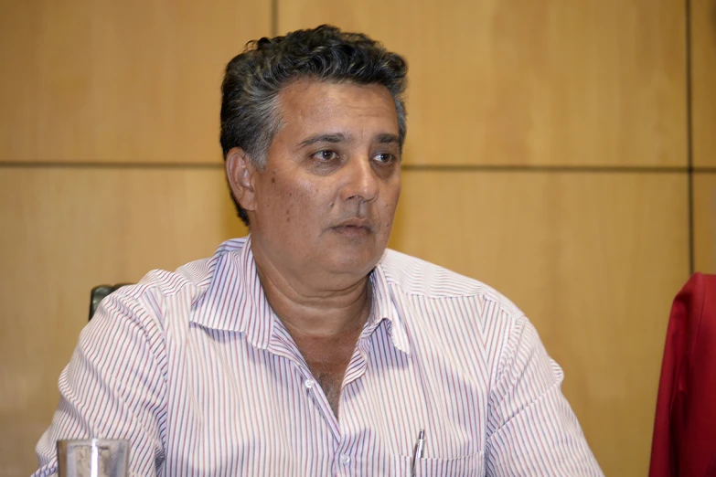 a man wearing a white shirt sitting next to a glass