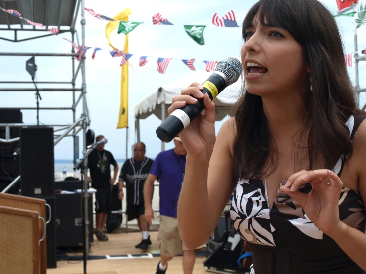 a woman holding a microphone while standing next to a stage