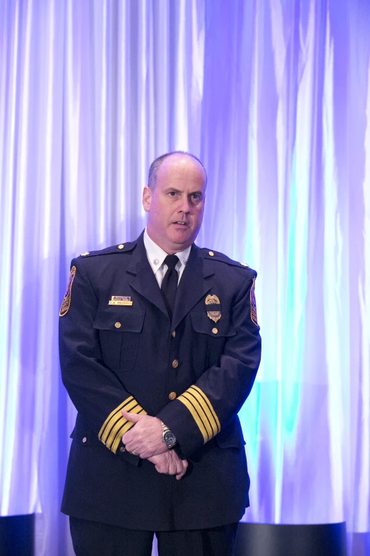 a man in military uniform standing in front of a blue curtain