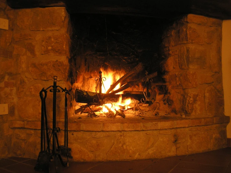 a fireplace with logs and flames lit up