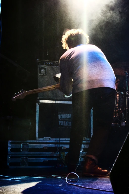 a man playing on a guitar while standing in front of a microphone