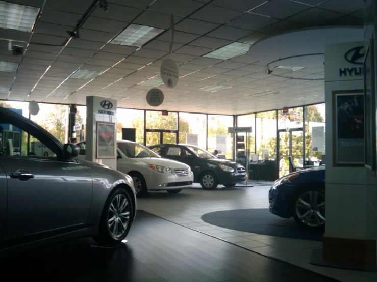 several vehicles sit in a garage with the sun shining through the windows