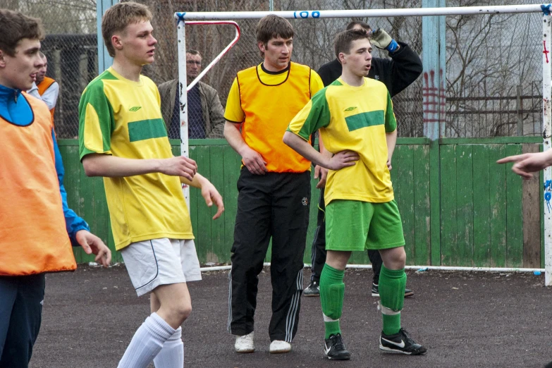 boys in colorful uniforms are standing around a soccer ball