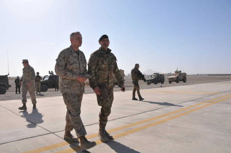 men in uniform stand on an airport tarmac