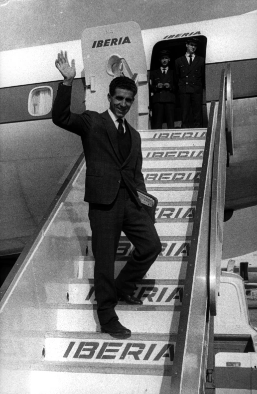 a man in business suit and tie standing on an airplane staircase
