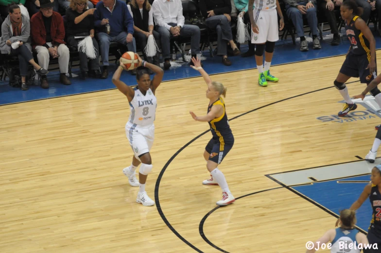 a woman in a white and yellow uniform is holding a basketball