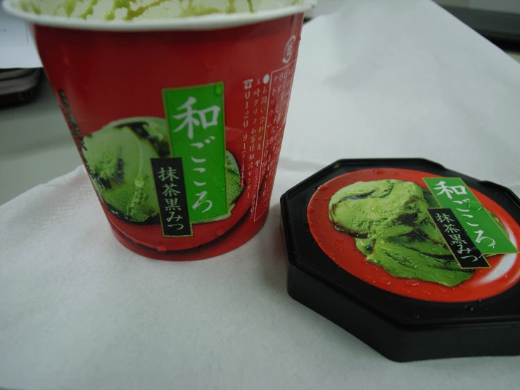 a container of green ice cream next to a cup with tea