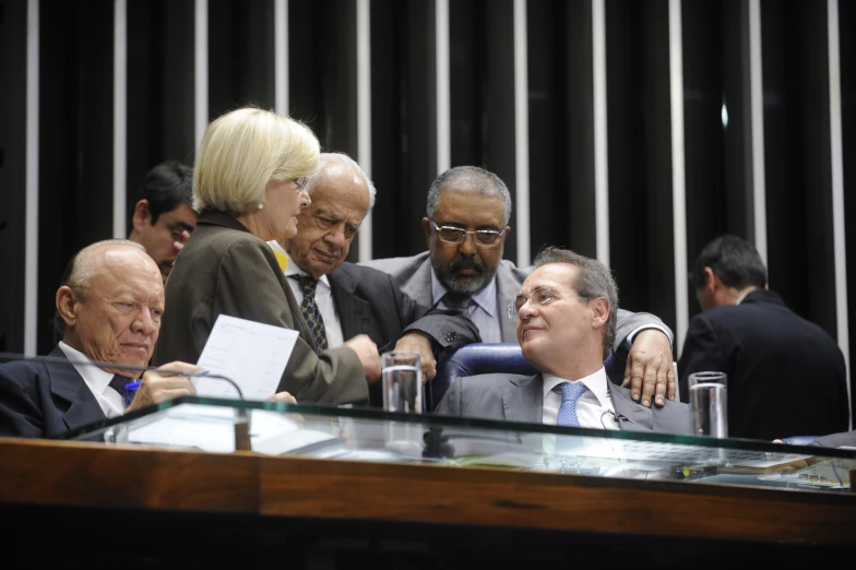 several men in suits and ties sitting at a meeting table