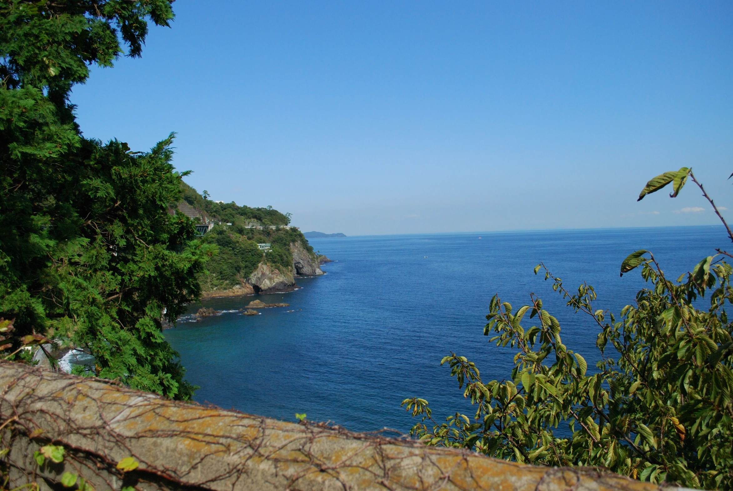 some blue water a large rock cliff and trees