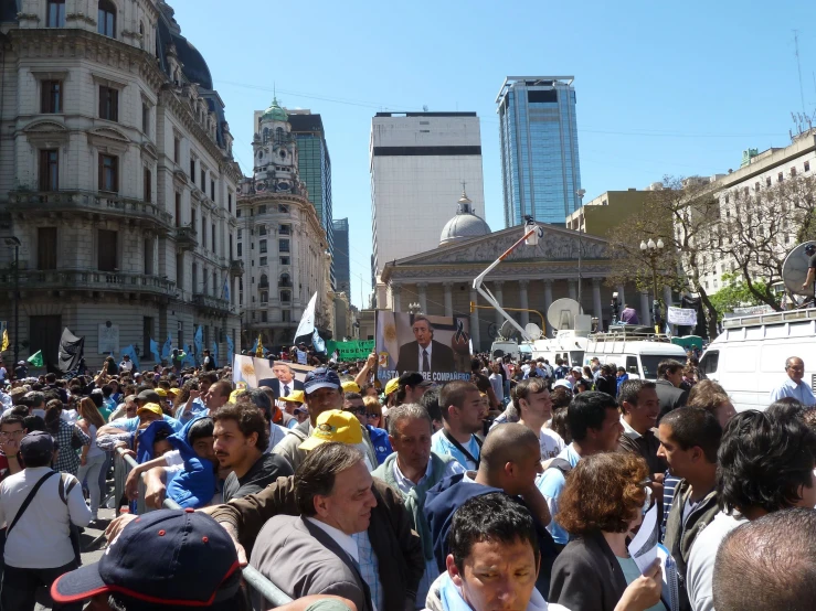 large crowd gathered in a city street near tall buildings