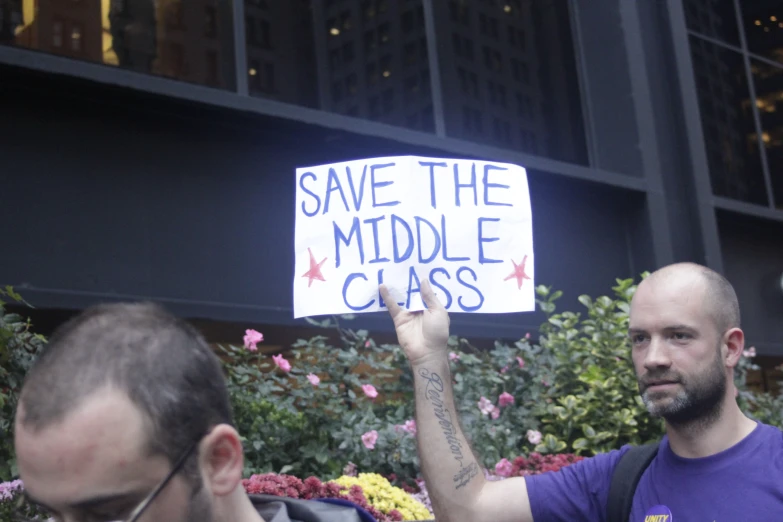 a man holding up a sign with words and symbols written on it