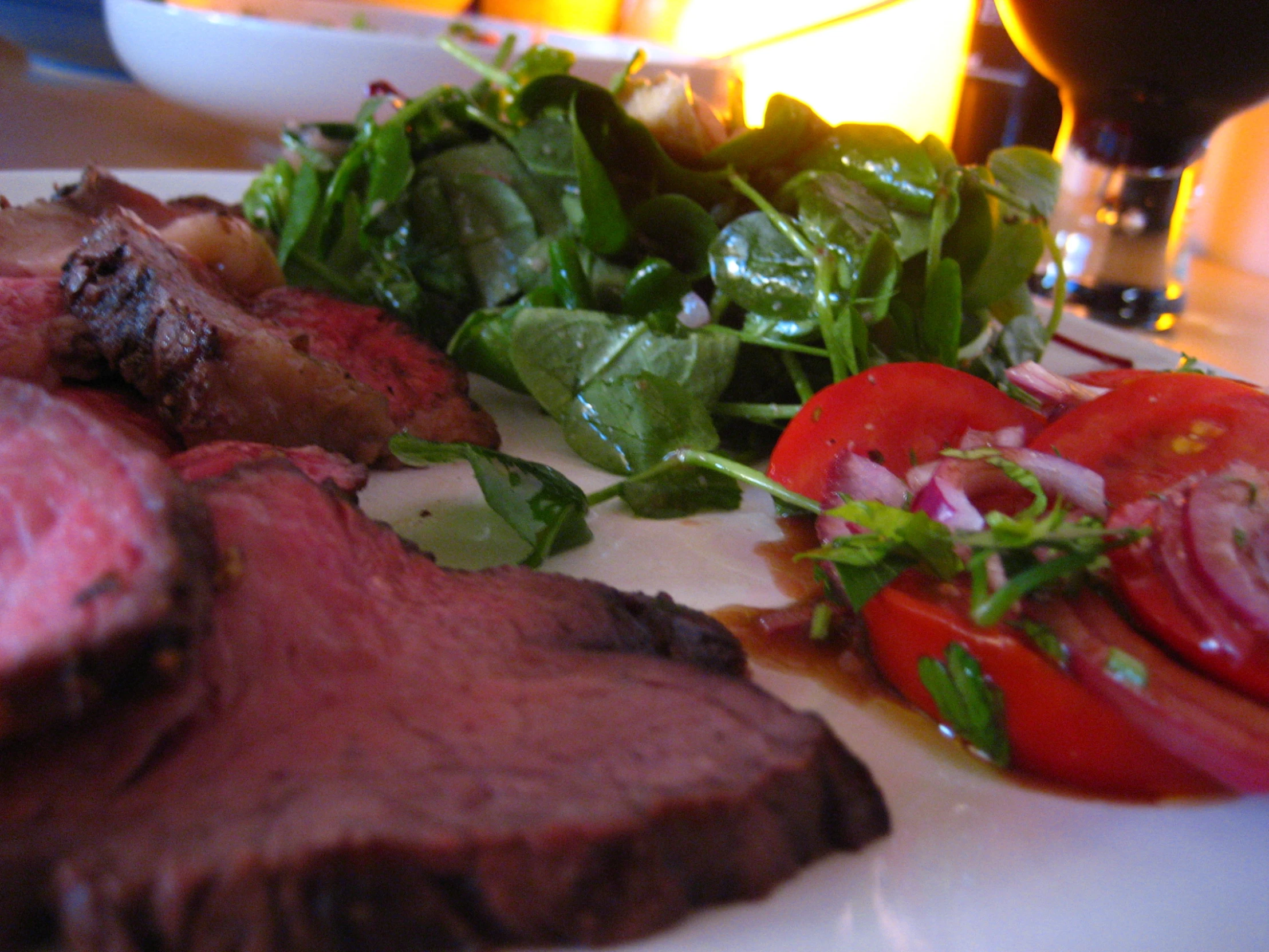 a closeup po of steak with green salad, and vegetables