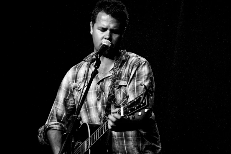 a man playing a guitar with a microphone