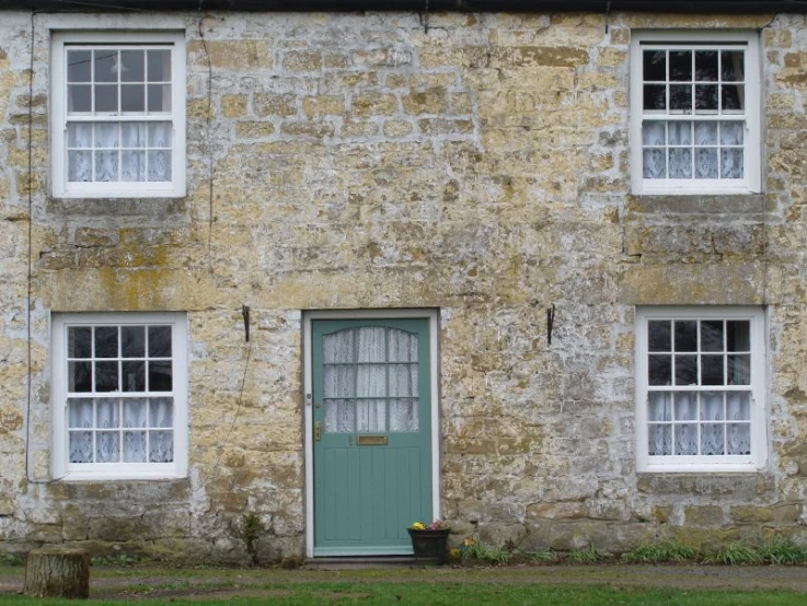 a stone building with white windows and a blue door