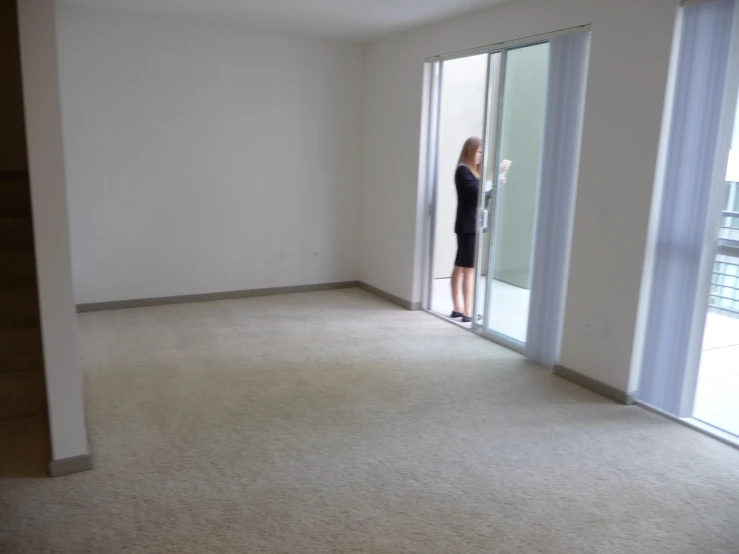 a woman standing in an empty room, with the door open