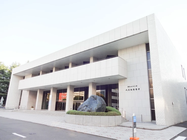 the exterior of a modern building with a large rock outside