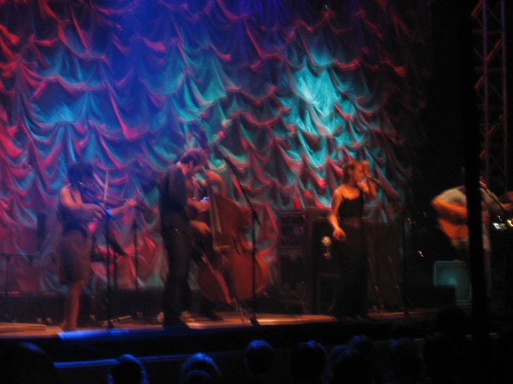 three band members performing on stage for a crowd