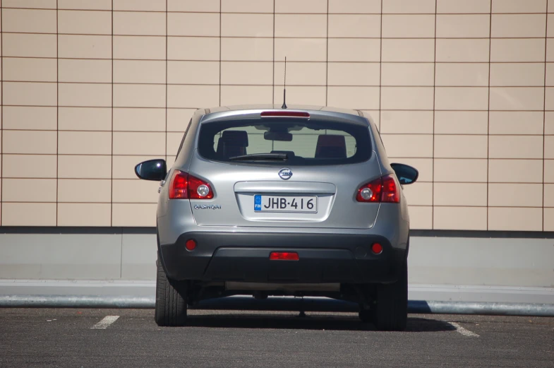 a silver car parked in front of a brown wall