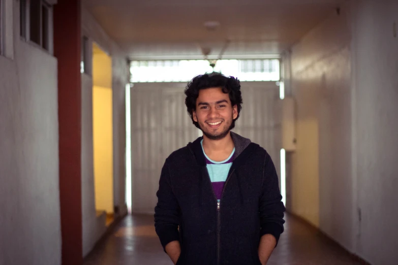 the young man is standing alone in the corridor