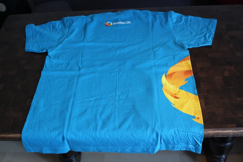 an unprinted shirt sits on a table, displaying the t - shirt has an orange parrot