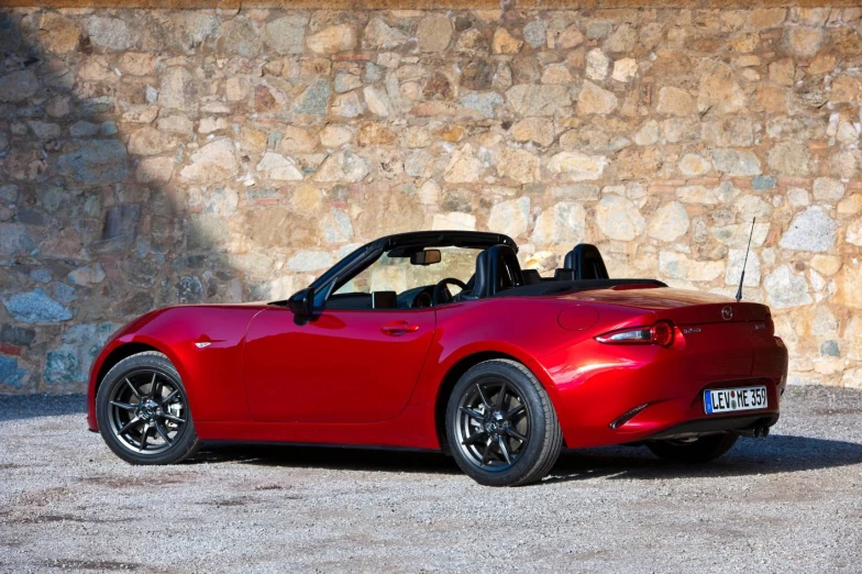 a red sports car is parked by the stone wall