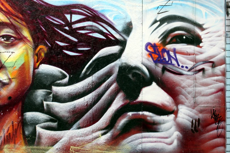 the image shows two face murals painted on a building wall
