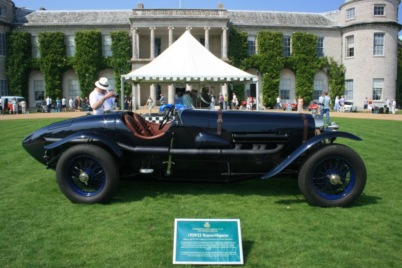 an antique car in front of a building with white tent