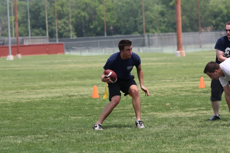 two men holding footballs on green grass during a game