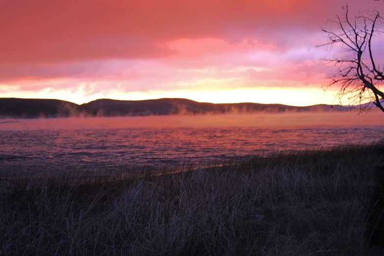 the sunset over some water with clouds