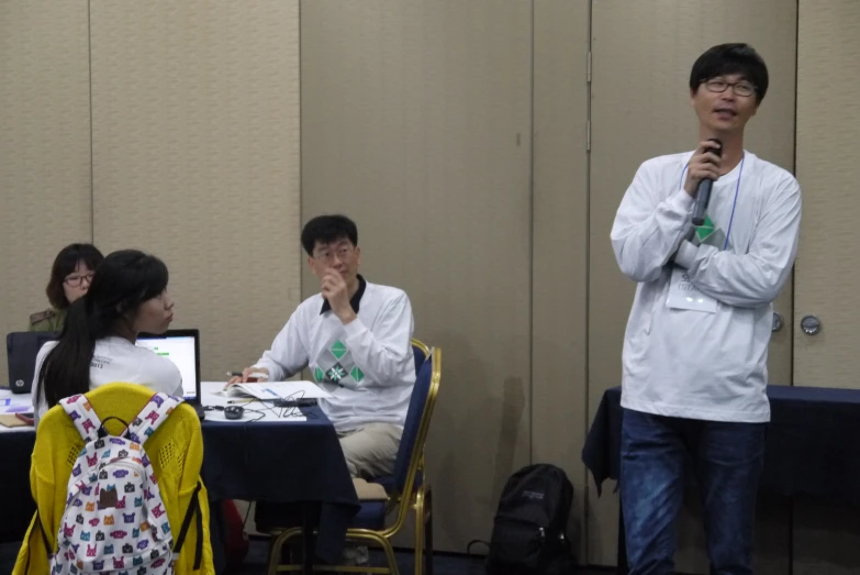 three people are sitting at a table with a microphone