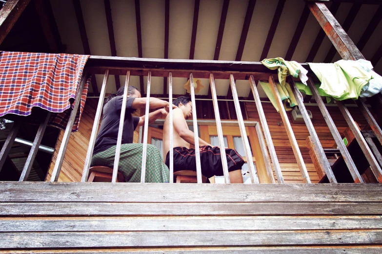 two men are on a porch with wood and metal railing