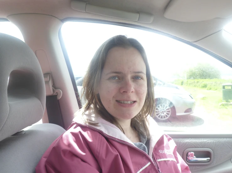 a girl wearing pink in the back seat of a car