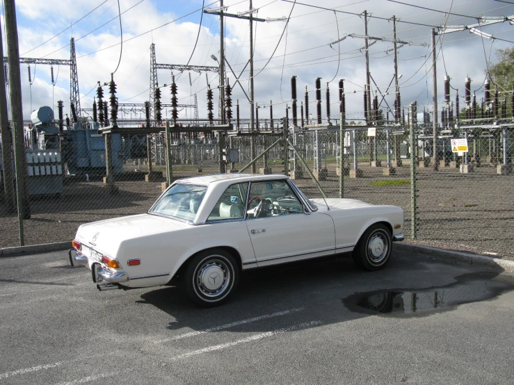 an old, white car is parked next to power lines