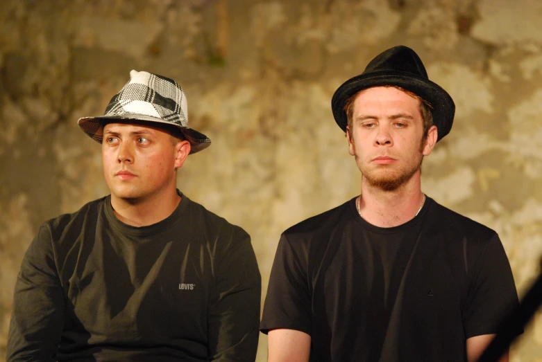 two men in black shirts and hats sitting down