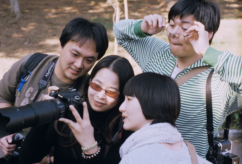 people standing next to each other taking pictures with camera